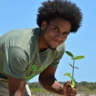 Forest Heights Academy 12th grader is excited to be on a fieldtrip planting his mangrove propagules.