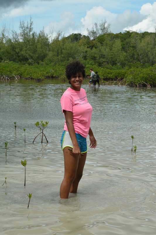 10th grade student at Forest Heights Academy collects three red mangrove seedlings that she will grow and care for during the next eight months in her Biology class.