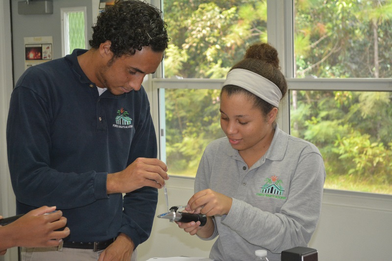 Before students from Forest Heights Academy use equipment in the field, they are practicing using it in the classroom first. Here students are placing a sample of liquid on a refractometer to determine the salinity of the liquid.