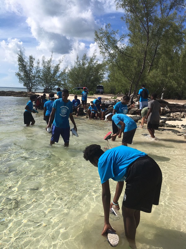 After an exciting mangrove field trip, students rinse their muddy shoes in the ocean before we head back to Abaco Central High School to plant their mangrove seedlings.