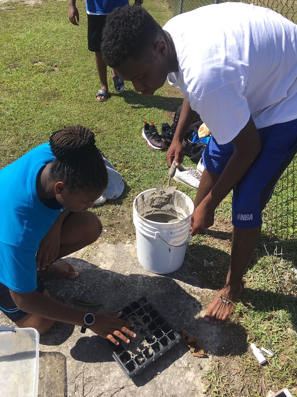 Playing in the Mud is Fun - Students from Abaco Central High School grade 10 Biology fill the plant flat with mud.