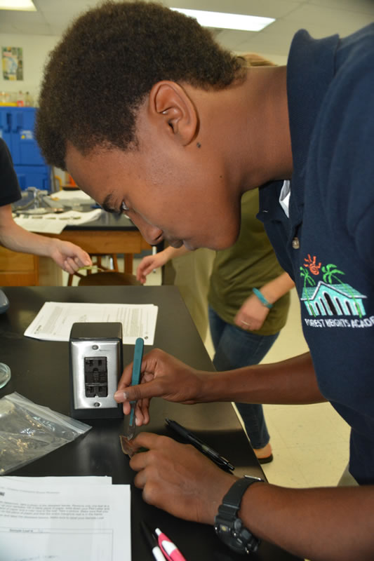 Forest Heights Academy Marine Biology student carefully uses a scalpel to cut or isolate a small piece of his diseased mangrove leaf. The student will place the leaf in agar and wait to see if fungus grows.