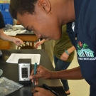 Forest Heights Academy Marine Biology student carefully uses a scalpel to cut or isolate a small piece of his diseased mangrove leaf. The student will place the leaf in agar and wait to see if fungus grows.