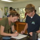 Ryann Rossi, PhD Candidate at North Carolina State University helps a student at Forest Heights Academy to isolate a piece of his diseased mangrove leaf.