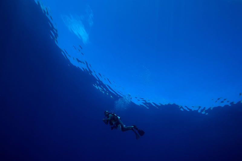Anderson Mayfield during a safety stop at the end of a dive under the ceiling of a glassy calm sea.