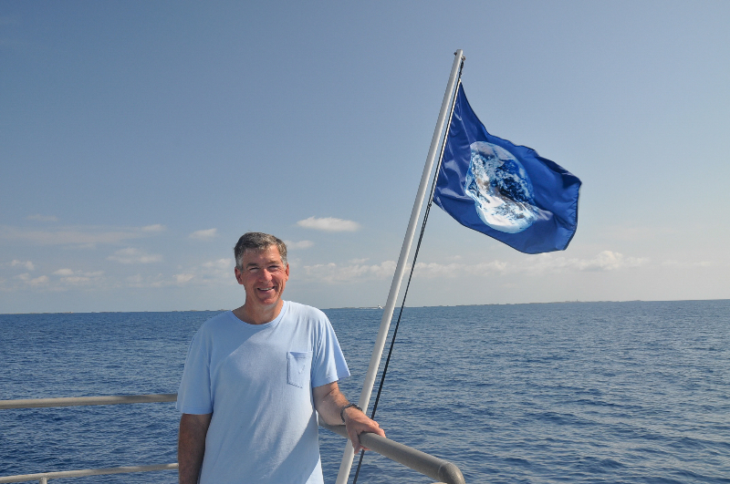 Phil Renaud stand next to an earth flag on the Golden Shadow.