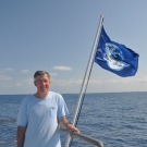 Phil Renaud stand next to an earth flag on the Golden Shadow.