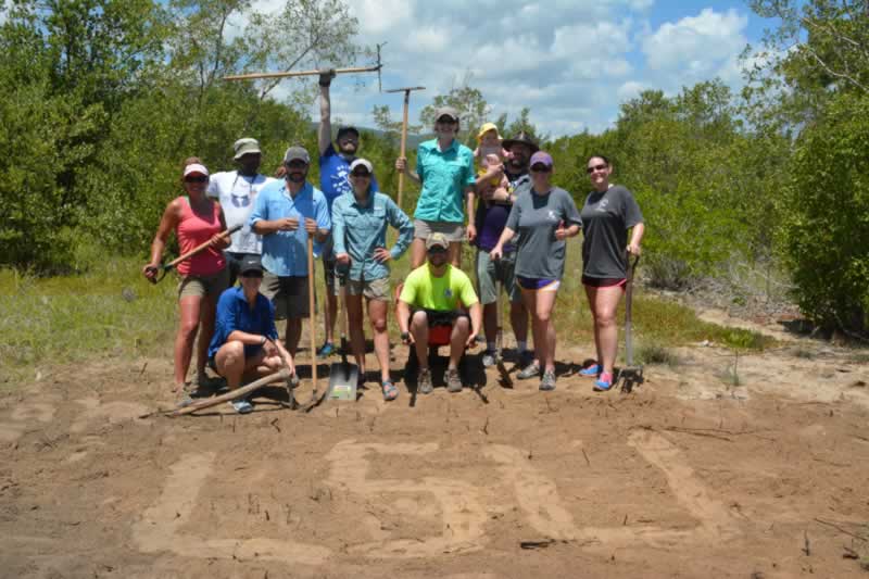 Alumni from Louisiana State University volunteer during their vacation to help remove old stumps and level soil at the JAMIN mangrove restoration site.