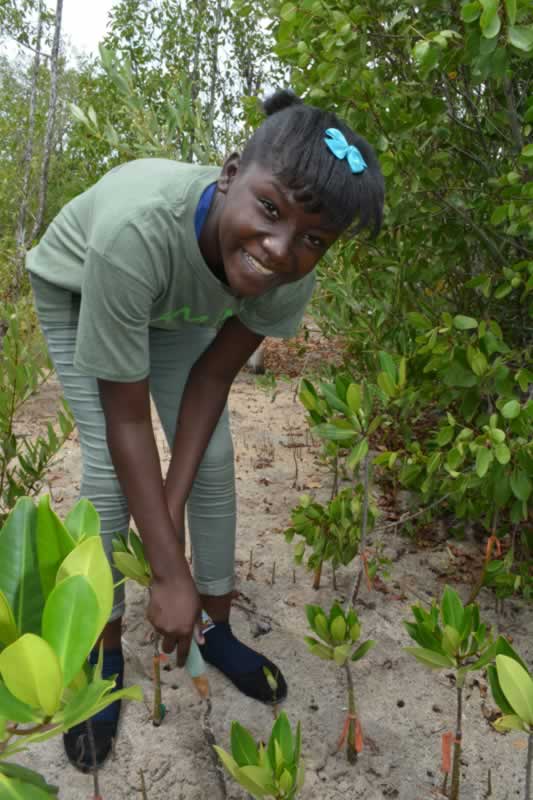 Tenth grade student from Holland High School pauses for a photo before she plants her mangrove propagule.