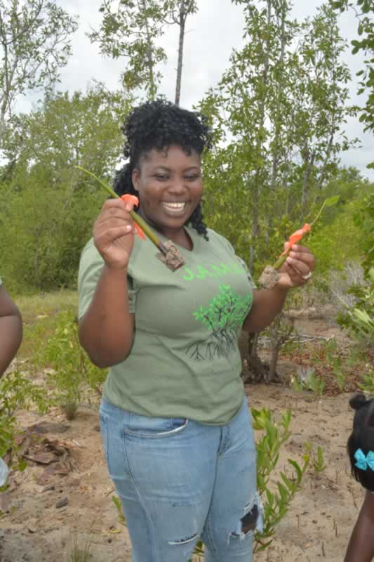 Holland High School Biology teacher Cherrida Walters gets her hands dirty and helps her students plant their mangroves.