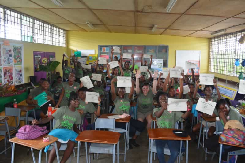 Students at William Knibb High School hold up their certificates to celebrate a successful end of the JAMIN program.