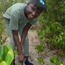 Tenth grade student from Holland High School pauses for a photo before she plants her mangrove propagule.