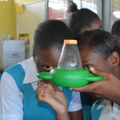 William Knibb student (on the right) is explaining to her classmate that there are mirrors inside the microviewer that reflect the image of the animals inside.