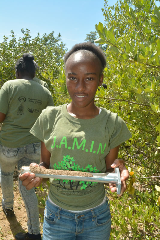 William Knibb High School student shows off her soil sample before she labels and places it in her collection bag. Later she and her group will determine the contents.