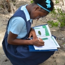 A student answers questions on her activity worksheet while on a field trip to a mangrove forest.