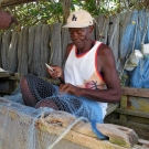 Back on shore, a fishermen mends his net.