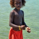 A young child in Nazareth community handlines for fish from the dock. 