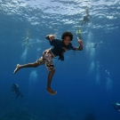 Local children free-diving to have their photos taken by scientists who are scuba diving.