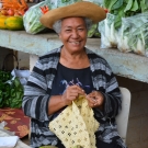 A woman weaving dried pandanus leaves at the farmer's market