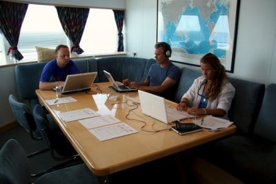 Global Research Expedition team members working and brushing up on reef species identification skills in the staff mess while underway