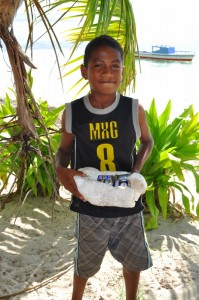 Young boy picking up batteries on beach after he heard the presentation.