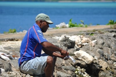 A Tonga fisherman cleans his catch by the water's edge at Vava'u.