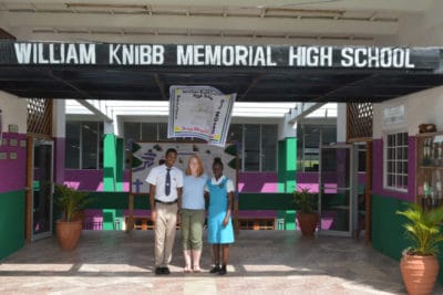 Intern Maggie Dillon stands out front of William Knibb High School in Jamaica with two students after a guided tour of the school.