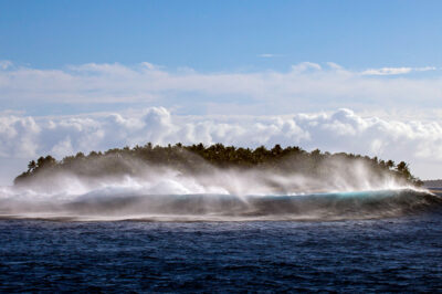 Waves crashing on the reef surrounding an island in Tonga. Coral reefs help protect coastal communities from large waves and storms.