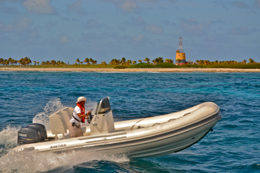 Hendra Agusman runs a tender past the lighthouse at Serranilla