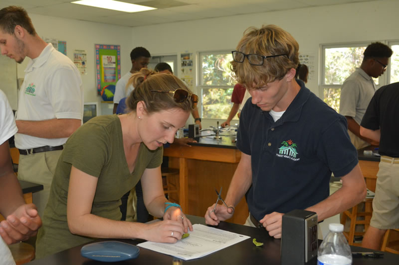 Ryann Rossi, PhD Candidate at North Carolina State University helps a student at Forest Heights Academy to isolate a piece of his diseased mangrove leaf.